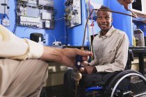 Instructor demonstrating air conditioner high pressure line to student in wheelchair in HVAC classroom — Stock Photo