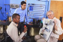 Instructor demonstrating air conditioner control system on demo board to students in HVAC classroom one student in wheelchair — Stock Photo