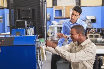 Student in wheelchair studying natural gas injector system on furnace with his classmate in HVAC classroom — Stock Photo