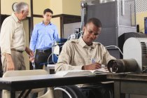 Lehrer diskutiert Brennstoffmischungssteuerung für Ofen im hvac Klassenzimmer, während ein Schüler im Rollstuhl Notizen macht — Stockfoto