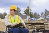 Construction supervisor with Spinal Cord Injury taking notes with concrete foundation forms in background — Stock Photo