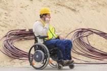 Supervisore di costruzione con lesione del midollo spinale su walkie talkie con cavi elettrici interrati — Foto stock