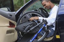Человек, у которого был менингит спинного мозга, садится в машину на инвалидном кресле — стоковое фото