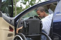 Человек, у которого был менингит спинного мозга, садится в машину на инвалидном кресле — стоковое фото