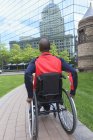 Hombre en silla de ruedas que tenía meningitis espinal moviéndose independientemente en la ciudad - foto de stock