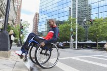 Uomo sulla sedia a rotelle che ha avuto meningite spinale andando oltre un marciapiede — Foto stock