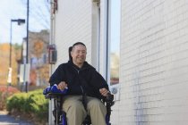 Человек с травмой спинного мозга и руки с повреждением нерва в моторизованной инвалидной коляске с помощью общественной улицы — стоковое фото