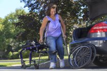 Frau mit Spina bifida nimmt Rollstuhl mit Krücken für Autofahrt auseinander — Stockfoto