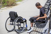 Homem que teve meningite espinhal com uma cadeira de rodas relaxante em um parque — Fotografia de Stock
