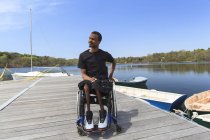 Человек, у которого был спинальный менингит в инвалидной коляске, сидящий на причале — стоковое фото