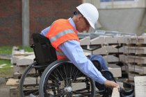 Ingénieur de projet avec une blessure à la moelle épinière dans un fauteuil roulant vérifiant le site — Photo de stock