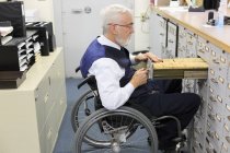 Чоловік з м'язовою дистрофією в інвалідному візку, що працює в офісі — стокове фото