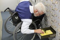 Чоловік з м'язовою дистрофією в інвалідному візку, що працює в офісі — стокове фото