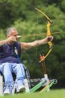 Homme avec blessure à la moelle épinière en fauteuil roulant visant son arc et sa flèche pour la pratique du tir à l'arc — Photo de stock