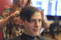 Homme à la mode avec une lésion de la moelle épinière dans un salon de coiffure se faire couper les cheveux — Photo de stock