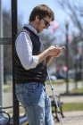 Jeune aveugle à un arrêt de bus utilisant la technologie d'assistance — Photo de stock