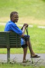 Человек с травматической травмой мозга расслабляется с тростью в парке — стоковое фото