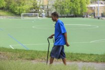 Uomo con Traumatico Lesioni Cerebrali fare una passeggiata con il bastone vicino a una scuola — Foto stock