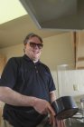 Uomo con cecità congenita lavare i piatti nella sua cucina — Foto stock