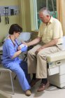 Krankenschwester mit Zerebralparese wickelt Patientin in Klinik die Hand ein — Stockfoto