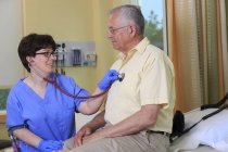 Krankenschwester mit Zerebralparese untersucht das Herz eines Patienten in einer Klinik — Stockfoto