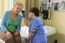 Медсестра с церебральным параличом проверяет уши пациента в клинике — стоковое фото