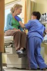 Infirmière avec paralysie cérébrale vérifiant la thyroïde d'un patient dans une clinique — Photo de stock