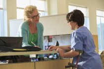 Медсестра з Церебралом Пальсі перевіряє з адміністрацією про записи пацієнта в клініці. — стокове фото
