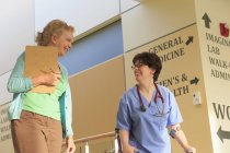 Krankenschwester mit Zerebralparese läuft mit einem Administrator den Flur einer Klinik hinunter — Stockfoto