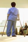 Krankenschwester mit Zerebralparese läuft mit ihren Stöcken durch den Flur einer Klinik — Stockfoto