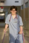 Krankenschwester mit Zerebralparese läuft mit ihren Stöcken durch den Flur einer Klinik — Stockfoto