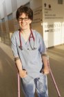 Медсестра с церебральным параличом идет по коридору клиники с тростями — стоковое фото