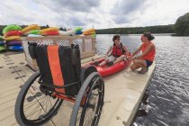 Istruttore aiutare una donna con una lesione del midollo spinale con l'utilizzo di un kayak — Foto stock