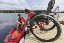 Istruttore aiutare una donna con una lesione del midollo spinale entrare in un kayak — Foto stock