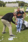 Hombre con lesión medular en un carro adaptativo en golf putting green con un instructor - foto de stock