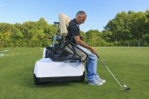 Man with spinal cord injury in an adaptive cart at golf putting green — Stock Photo