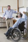 Два инженера проекта говорят о работе, один в инвалидной коляске с травмой спинного мозга — стоковое фото