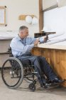 Ingegnere del progetto che utilizza tablet per controllare i piani di cantiere, mentre in sedia a rotelle con una lesione del midollo spinale — Foto stock