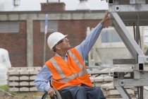 Ingeniero de proyecto con lesión de médula espinal en silla de ruedas en el lugar de trabajo - foto de stock