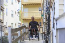 Homem em uma cadeira de rodas que tinha meningite espinhal em uma rampa em seu prédio de apartamentos — Fotografia de Stock