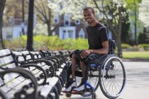 Homme en fauteuil roulant qui avait une méningite vertébrale assis près d'un banc de parc — Photo de stock