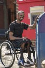 Man in a wheelchair who had Spinal Meningitis using the public mail box — Stock Photo