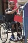 Homem em uma cadeira de rodas que tinha meningite espinhal colocando uma carta em uma caixa de correio público — Fotografia de Stock