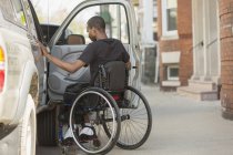 Чоловік у інвалідному візку, який мав спинний менінгіт, увійшов у свій доступний транспортний засіб — стокове фото