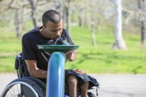 Человек в инвалидном кресле, у которого был спинальный менингит, используя фонтан с общественной водой — стоковое фото