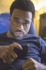Hombre afroamericano con parálisis cerebral usando su celular en casa - foto de stock
