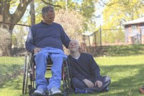 Padre con lesione al midollo spinale e figlio con sindrome di Down che sta per giocare a baseball nel parco — Foto stock