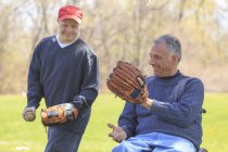 Padre con lesione al midollo spinale e figlio con sindrome di Down che sta per giocare a baseball nel parco — Foto stock