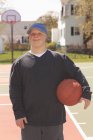 Portrait d'un jeune homme trisomique tenant le basket au pair — Photo de stock