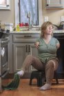 Donna con sindrome di TAR raccogliendo un asciugamano da cucina con i piedi — Foto stock